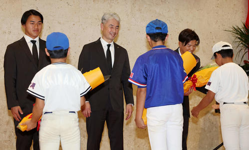 石垣空港に到着したロッテ西川（左）、吉井監督（中央）、中村奨は野球少年たちから笑顔で花束を受け取る（撮影・宮地輝）
