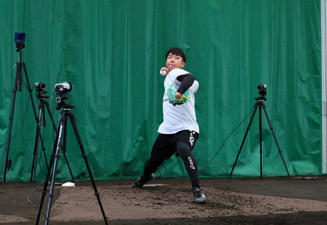 合同自主トレのブルペンで、たくさんのカメラに囲まれ投球練習をする阪神村上（撮影・藤尾明華）