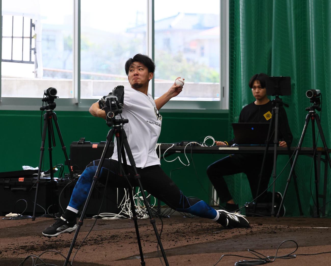 合同自主トレのブルペンで、たくさんのカメラに囲まれ投球練習をする阪神伊藤将（撮影・藤尾明華）
