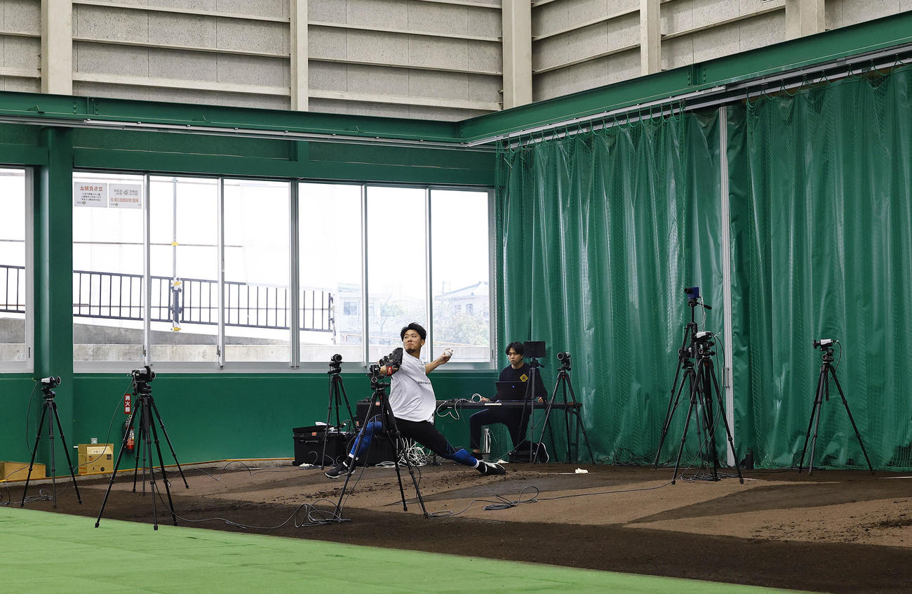 合同自主トレのブルペンで、たくさんのカメラに囲まれ投球練習をする阪神伊藤将（撮影・藤尾明華）
