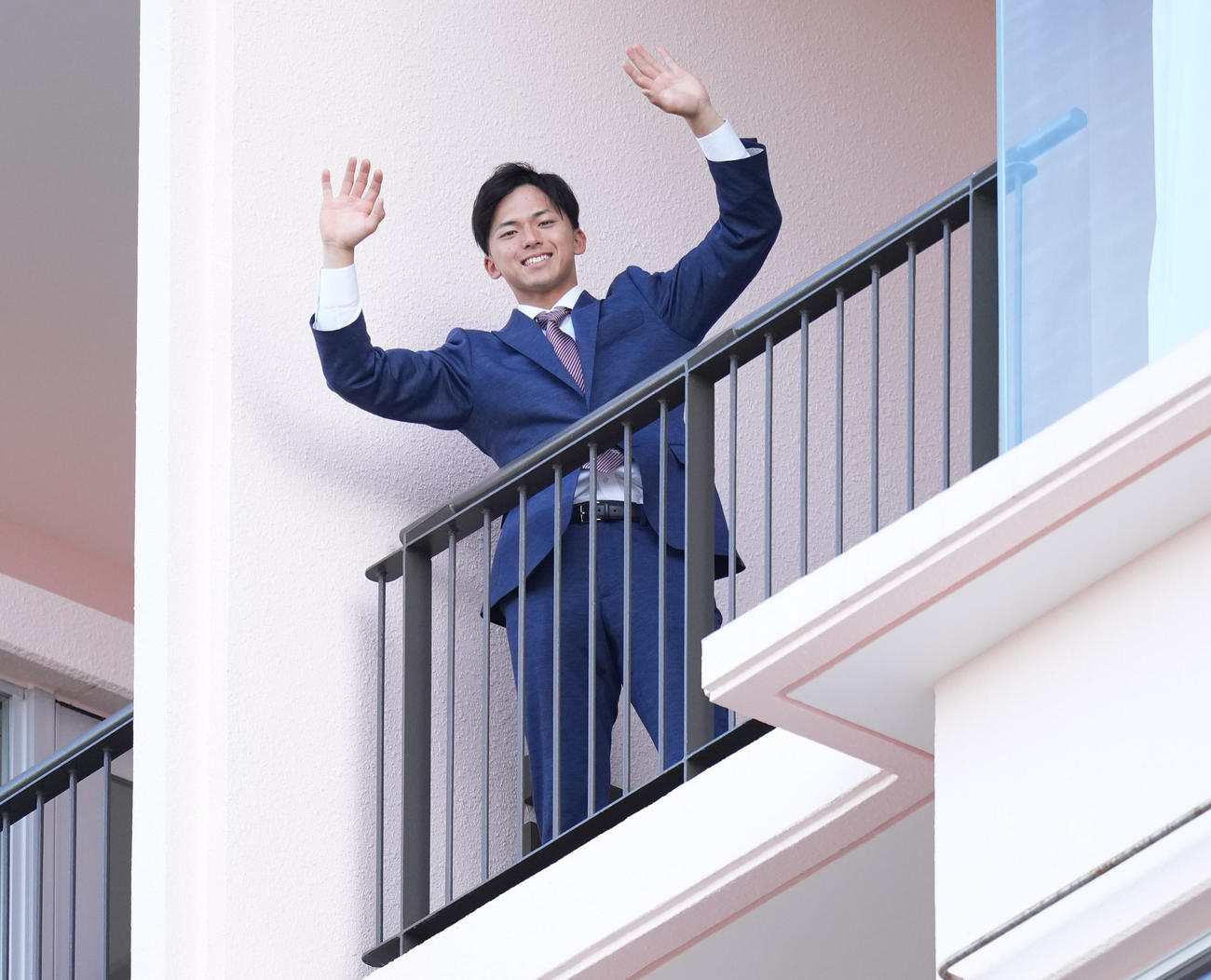 沖縄入りし、宿舎のベランダから手を振る楽天宗山（撮影・鈴木みどり）