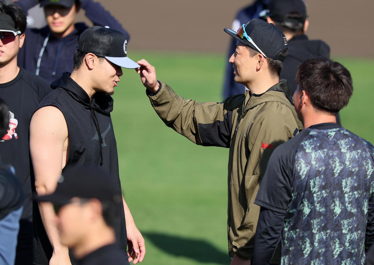 先乗り自主トレ2日目、佐藤輝（左）の帽子を見る岩崎（撮影・加藤哉）