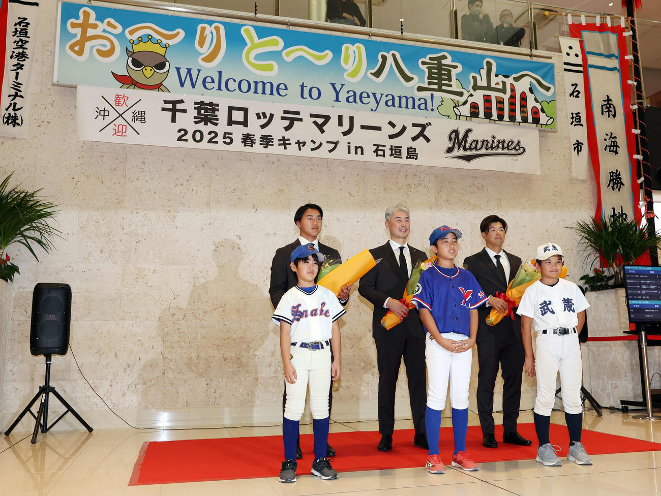 石垣空港に到着したロッテ西川（左）、吉井監督（中央）、中村奨は野球少年たちから花束を受け取った（撮影・宮地輝）