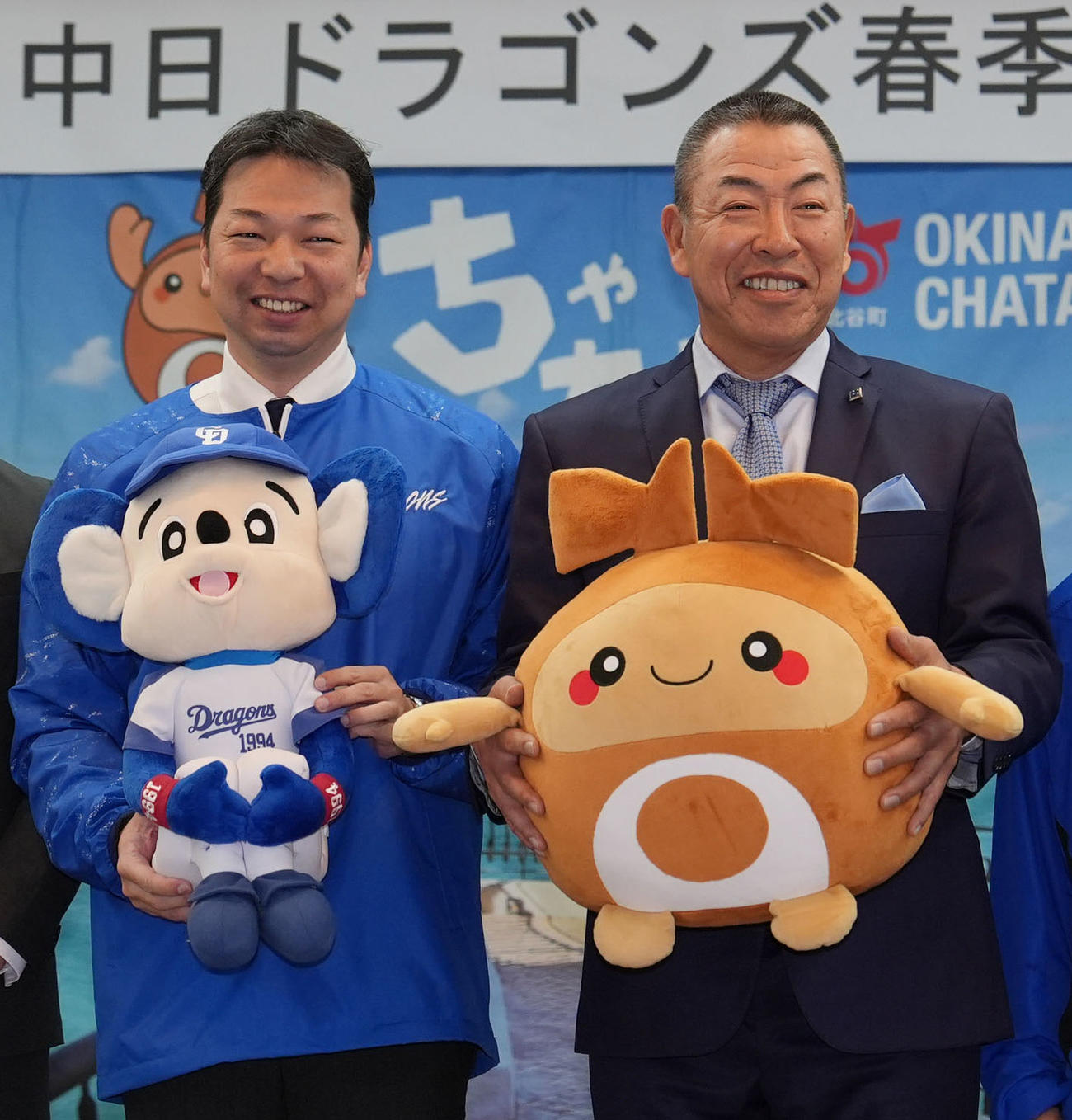 北谷町役場を表敬訪問に訪れお互いのマスコットぬいぐるみを手に笑顔を見せる、左から渡久地町長と井上監督（撮影・森本幸一）