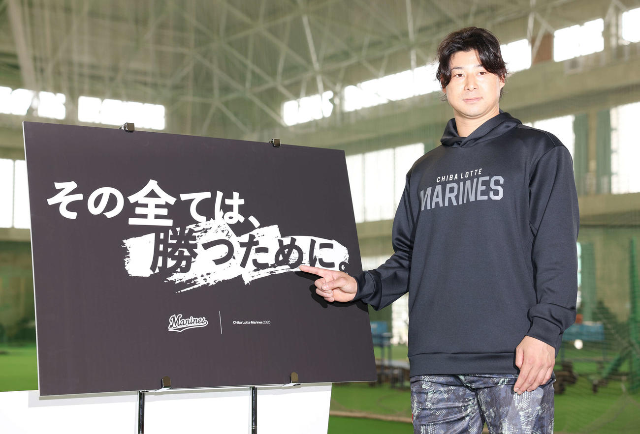 今季のチームスローガン「その全ては、勝つために。」を指さすロッテ藤岡（撮影・宮地輝）
