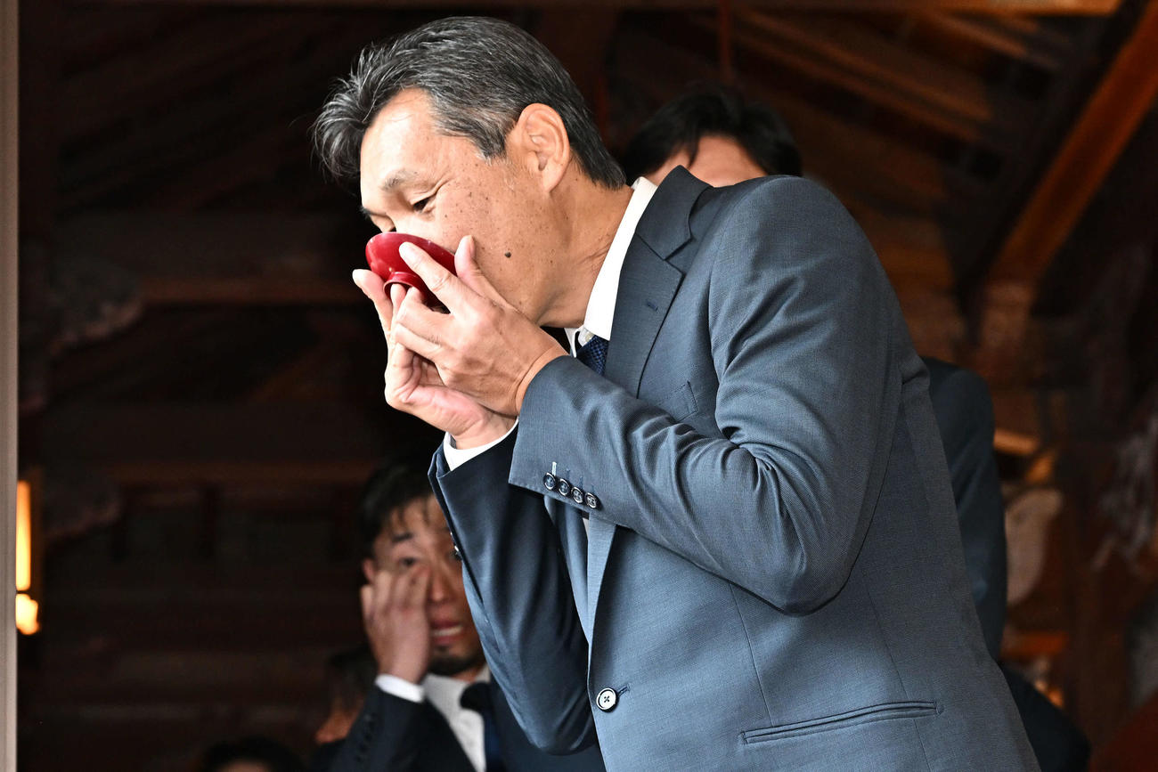 榎原神社で無事息災祈願を終えお神酒を飲む西武西口監督（撮影・滝沢徹郎）