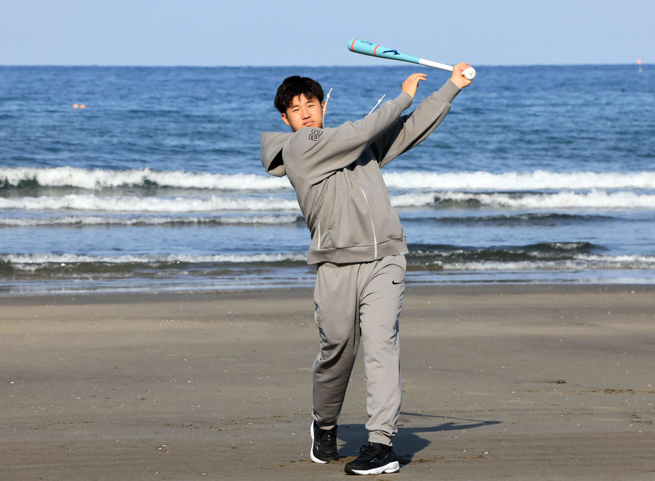 青島海岸の海を背に素振りする巨人石塚（撮影・浅見桂子）