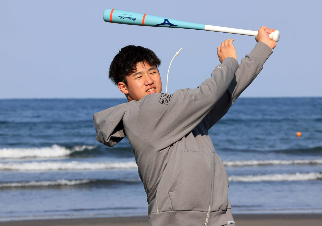 青島海岸の海を背に素振りする巨人石塚（撮影・浅見桂子）