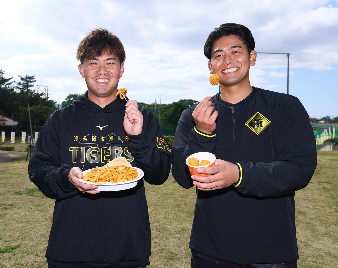阪神のキャンプ地にあるパーラー宜野座で発売される新商品のキリキリポテトとチバリヨーボールを手にする桐敷（左）と岡留（撮影・藤尾明華）