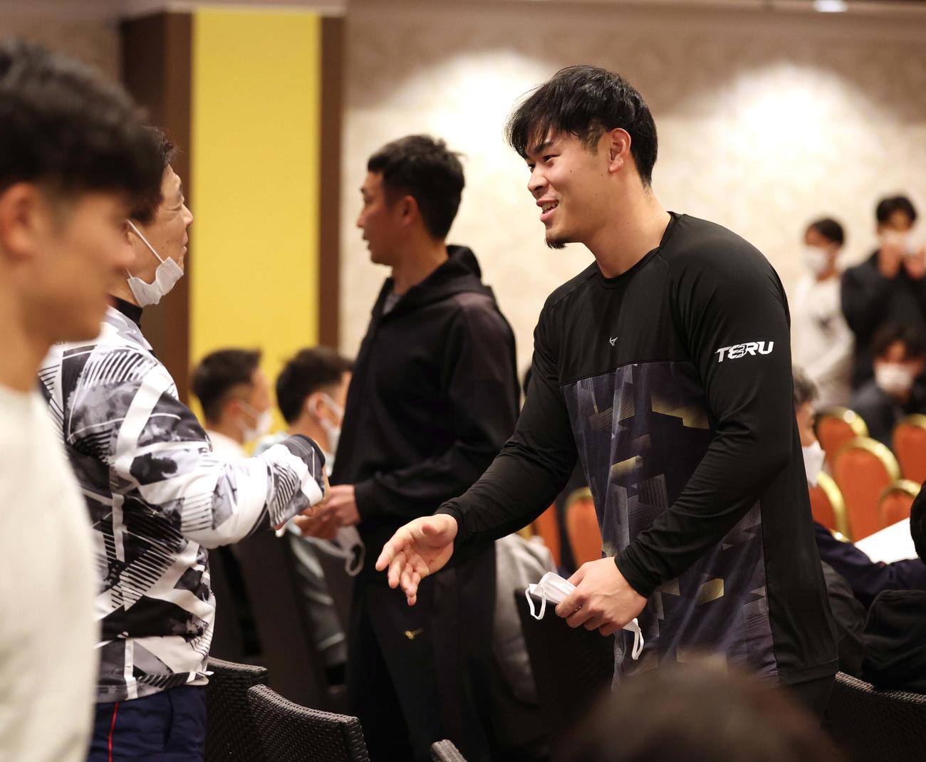 ミーティング会場に入った佐藤輝（右）は平田2軍監督に笑顔で挨拶をする