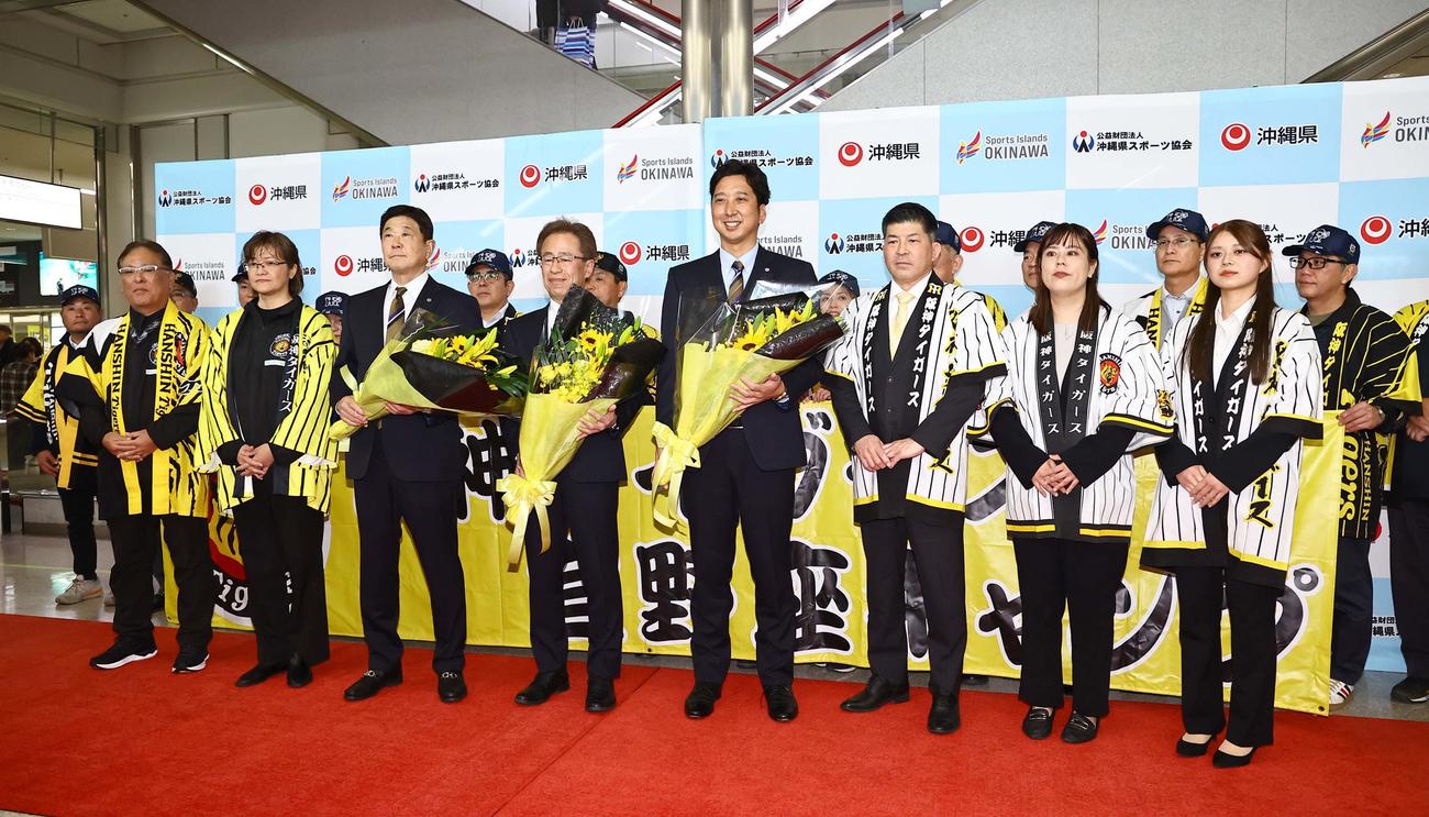藤川監督（右から4人目）、粟井球団社長、平田2軍監督は那覇空港での歓迎セレモニーで笑顔を見せる（撮影・上田博志）