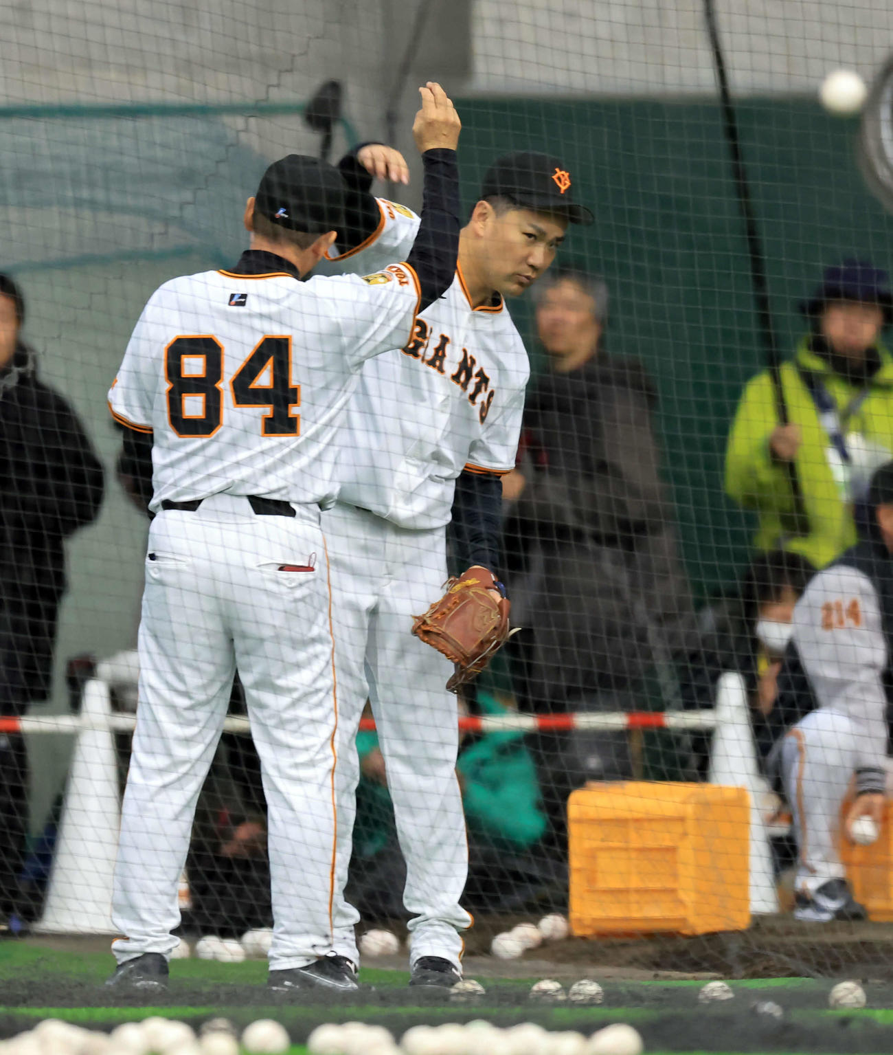 キャンプ初日、ブルペン横で巨人久保巡回投手コーチ（手前）から投球フォームの指導を受ける田中将（撮影・浅見桂子）