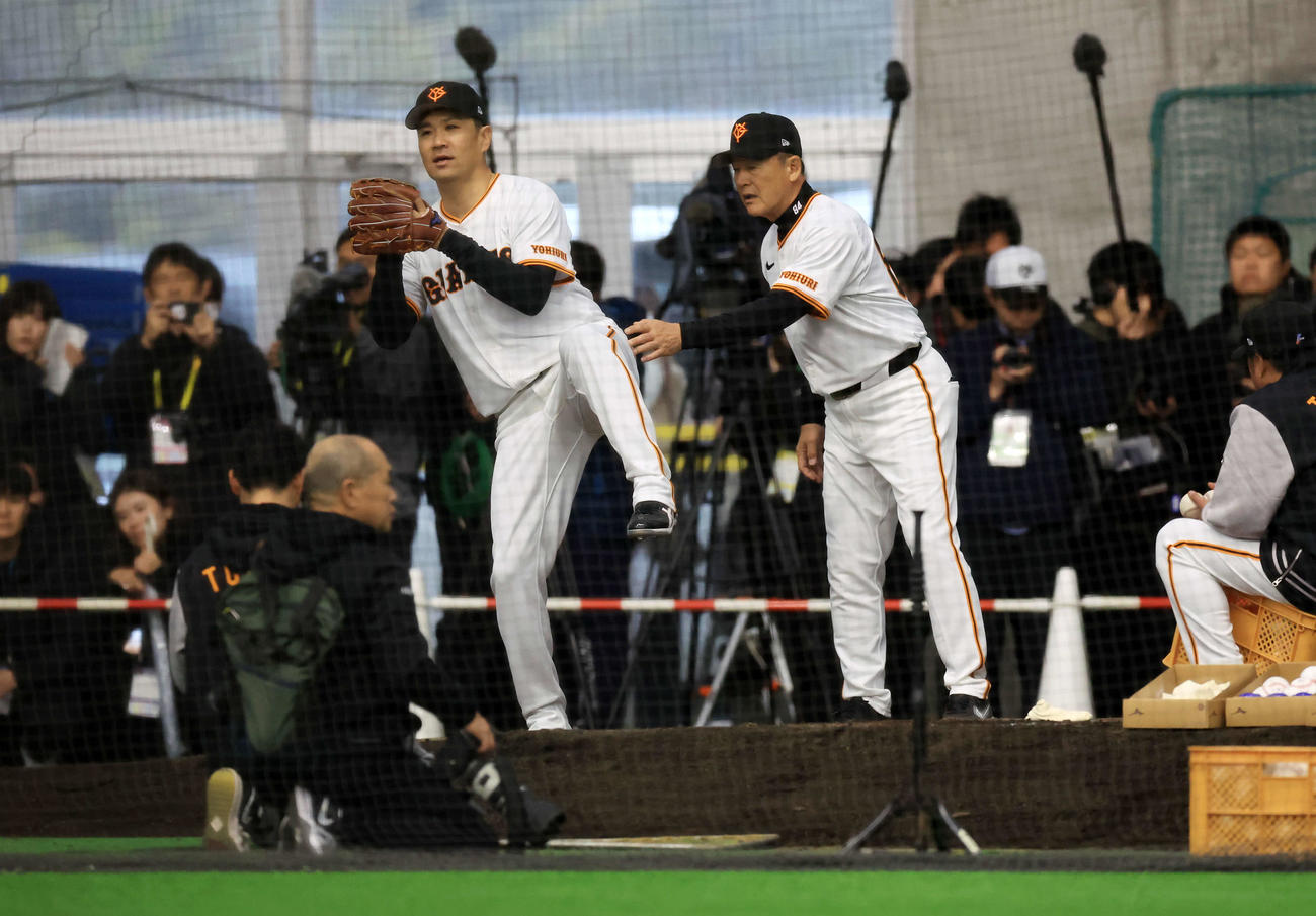 キャンプ初日、大勢の報道陣が見つめる中、逆傾斜のブルペンで巨人久保巡回投手コーチ（右）から投球フォームの指導を受ける田中将（撮影・浅見桂子）