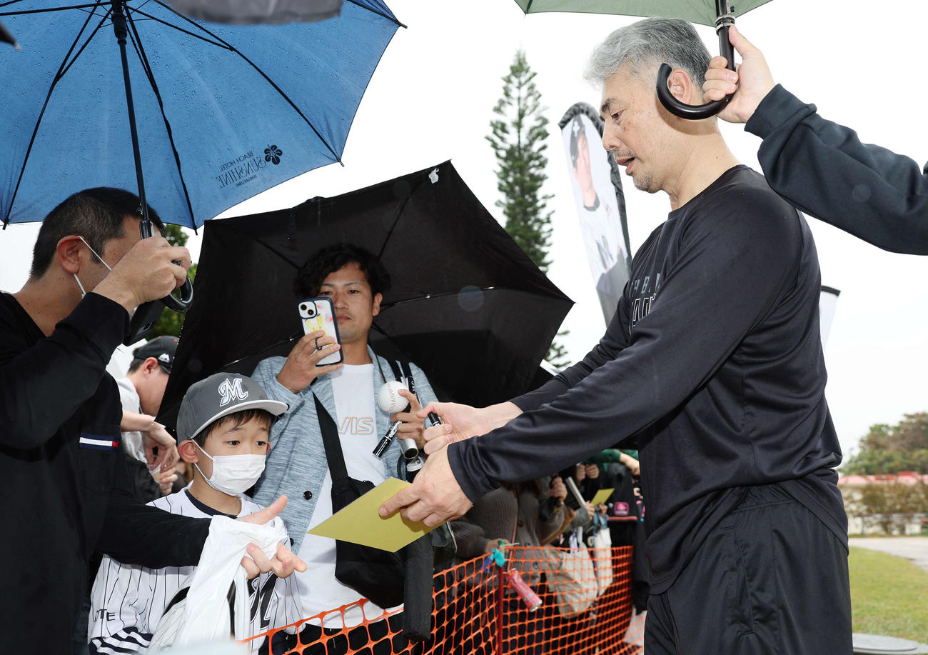 雨が降る中ファンにサインをするロッテ吉井監督（撮影・宮地輝）