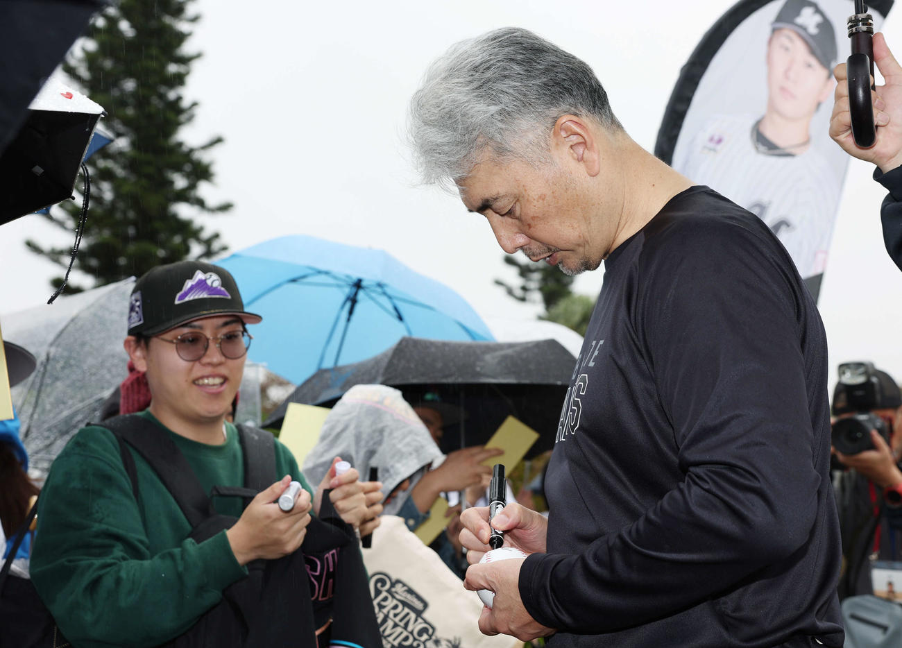 雨が降る中ファンにサインをするロッテ吉井監督（撮影・宮地輝）