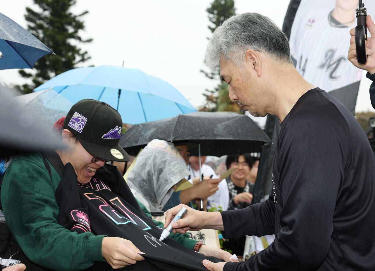 雨が降る中ファンにサインをするロッテ吉井監督（撮影・宮地輝）