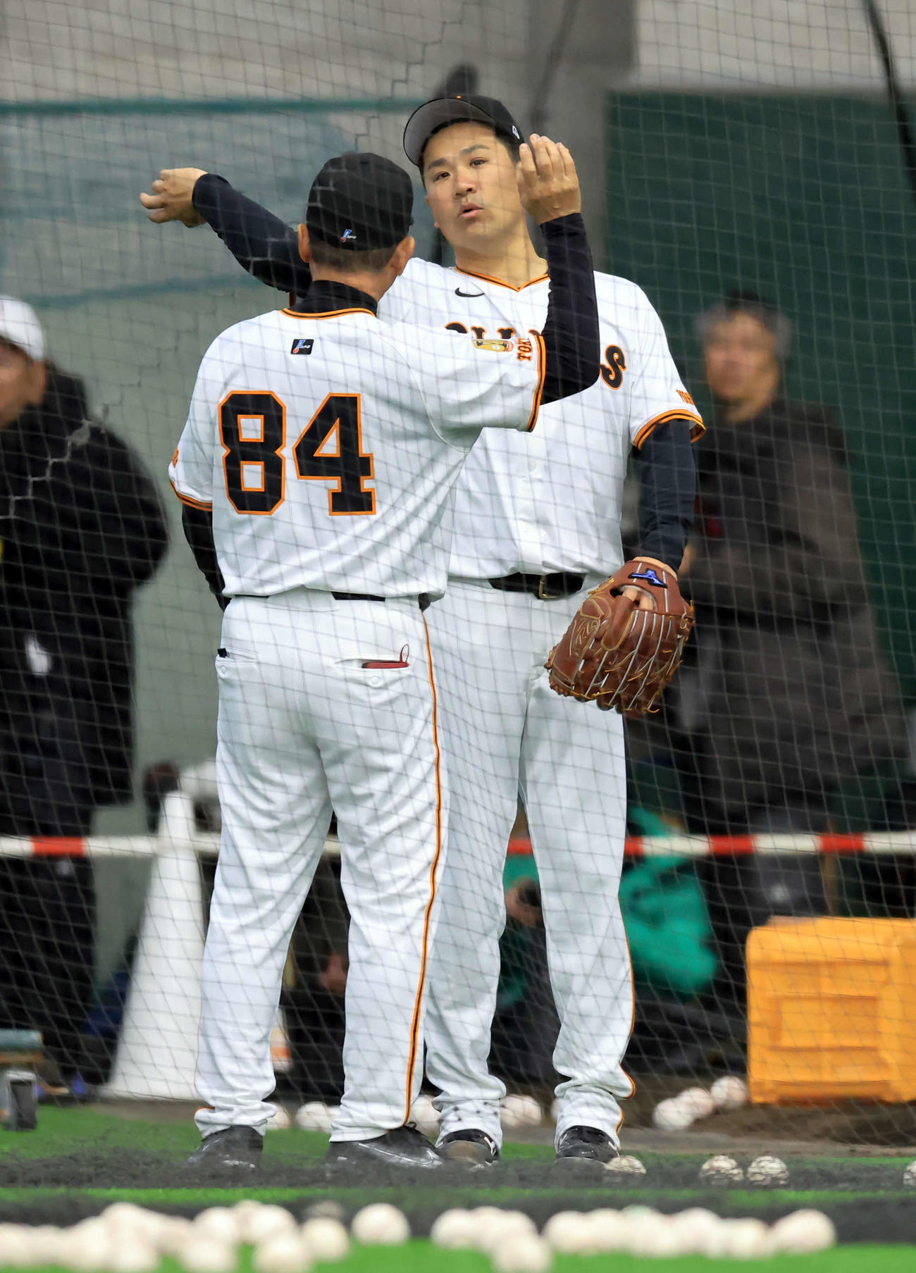 キャンプ初日、ブルペン横で巨人久保巡回投手コーチ（手前）から投球フォームの指導を受ける田中将（撮影・浅見桂子）