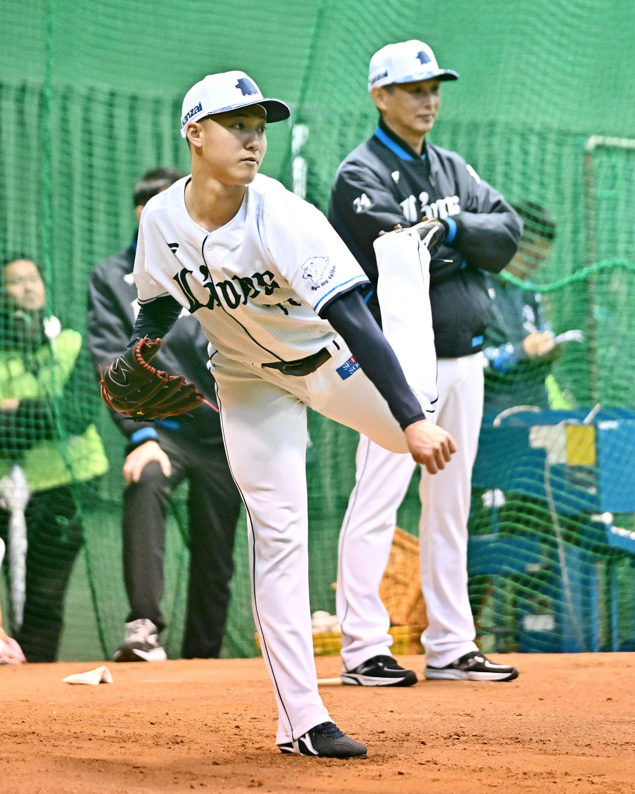 ブルペンで投球練習する西武菅井。後方は西口監督（撮影・滝沢徹郎）