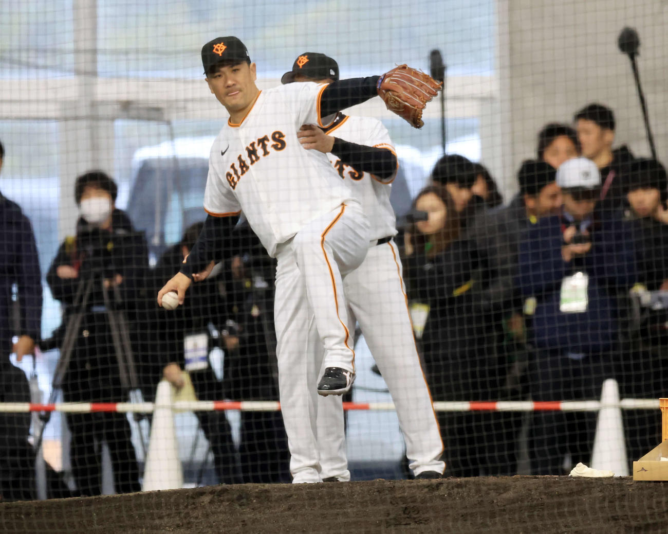 キャンプ初日、大勢の報道陣が見つめる中、逆傾斜のブルペンで巨人久保巡回投手コーチ（奥）から投球フォームの指導を受ける田中将（撮影・浅見桂子）