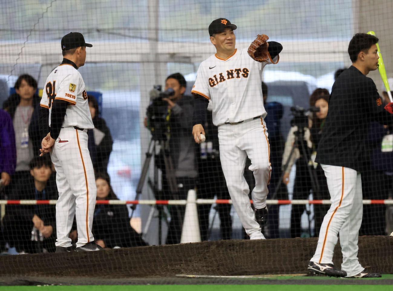 キャンプ初日、大勢の報道陣が見つめる中、逆傾斜のブルペンで巨人久保巡回投手コーチ（左）から投球フォームの指導を受ける田中将は、よろけてしまう（撮影・浅見桂子）