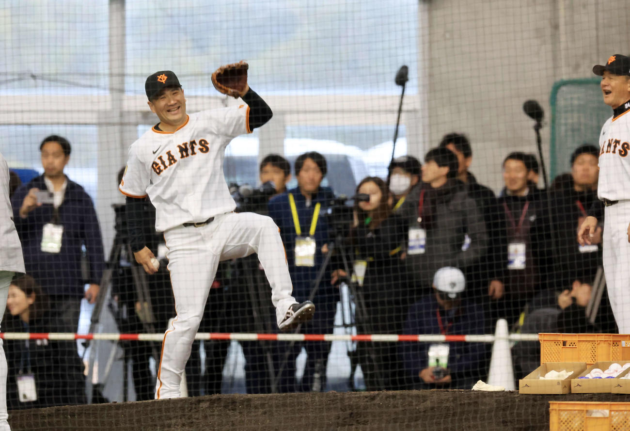 キャンプ初日、大勢の報道陣が見つめる中、逆傾斜のブルペンで巨人久保巡回投手コーチ（右端）から投球フォームの指導を受ける田中将は、よろけて苦笑する（撮影・浅見桂子）