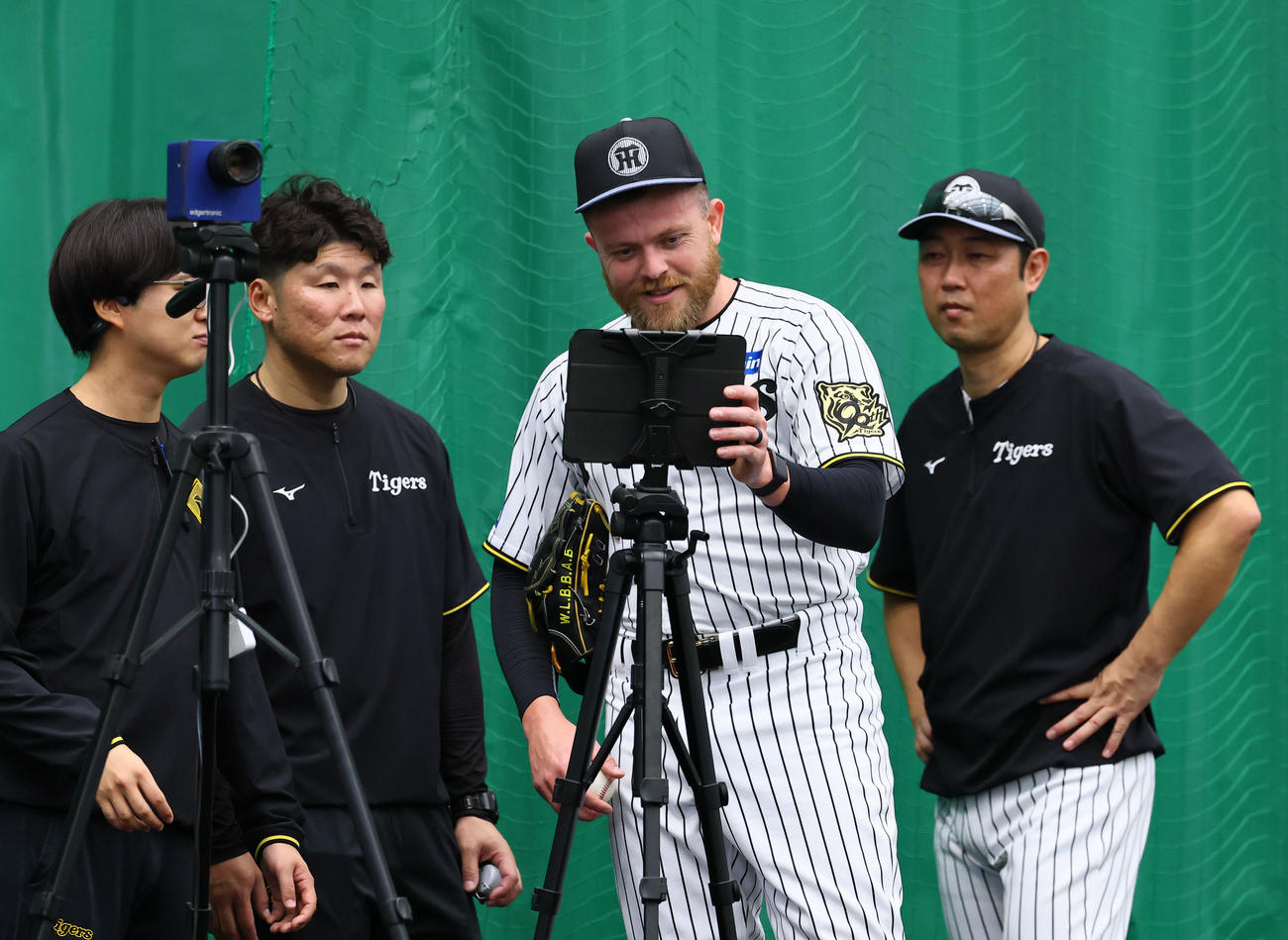 投球練習後、タブレットを見るビーズリー（右から2人目）（撮影・藤尾明華）