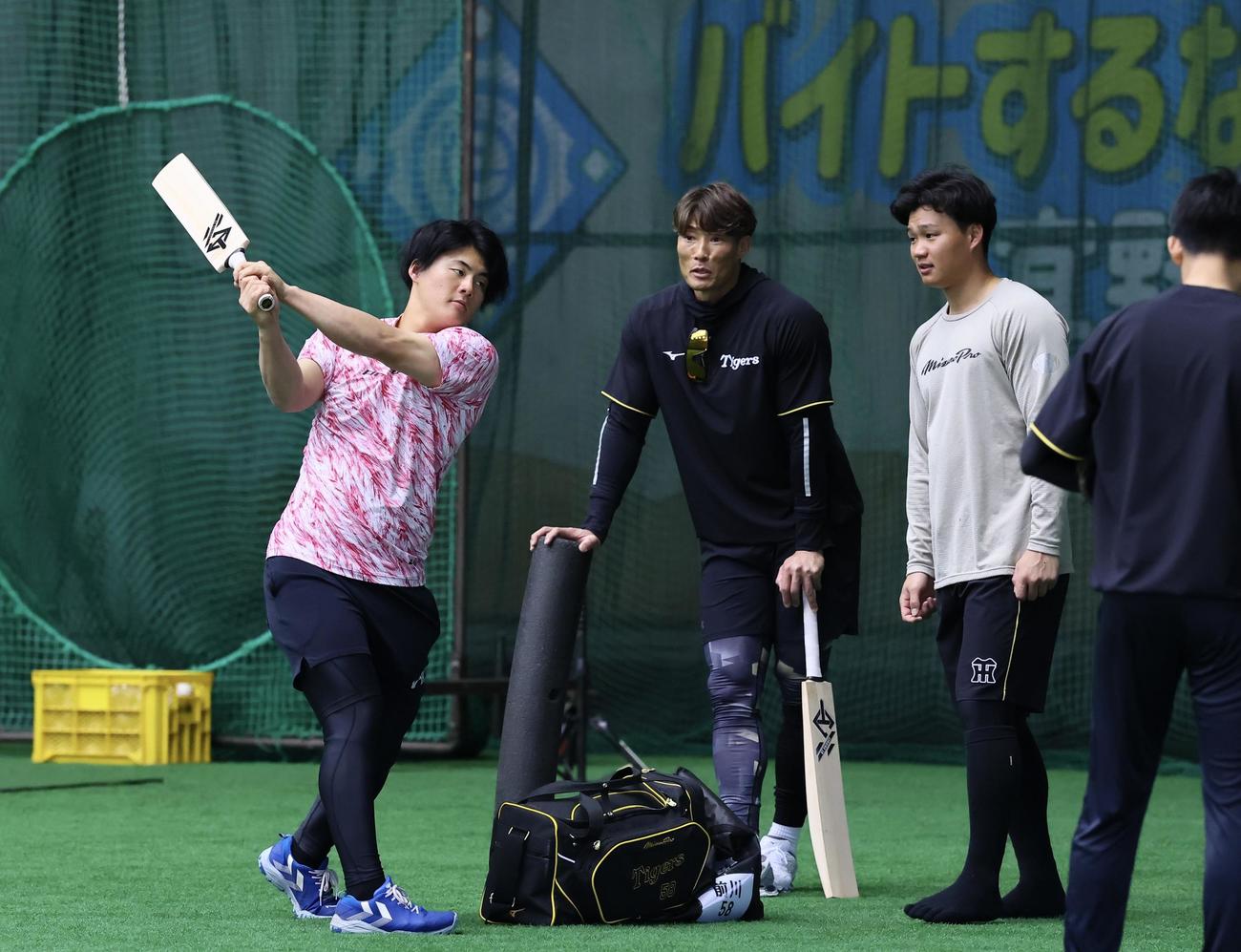 糸井臨時コーチ（中央）に渡されたクリケット型バットを振る阪神前川（左）。右は森下（撮影・藤尾明華）