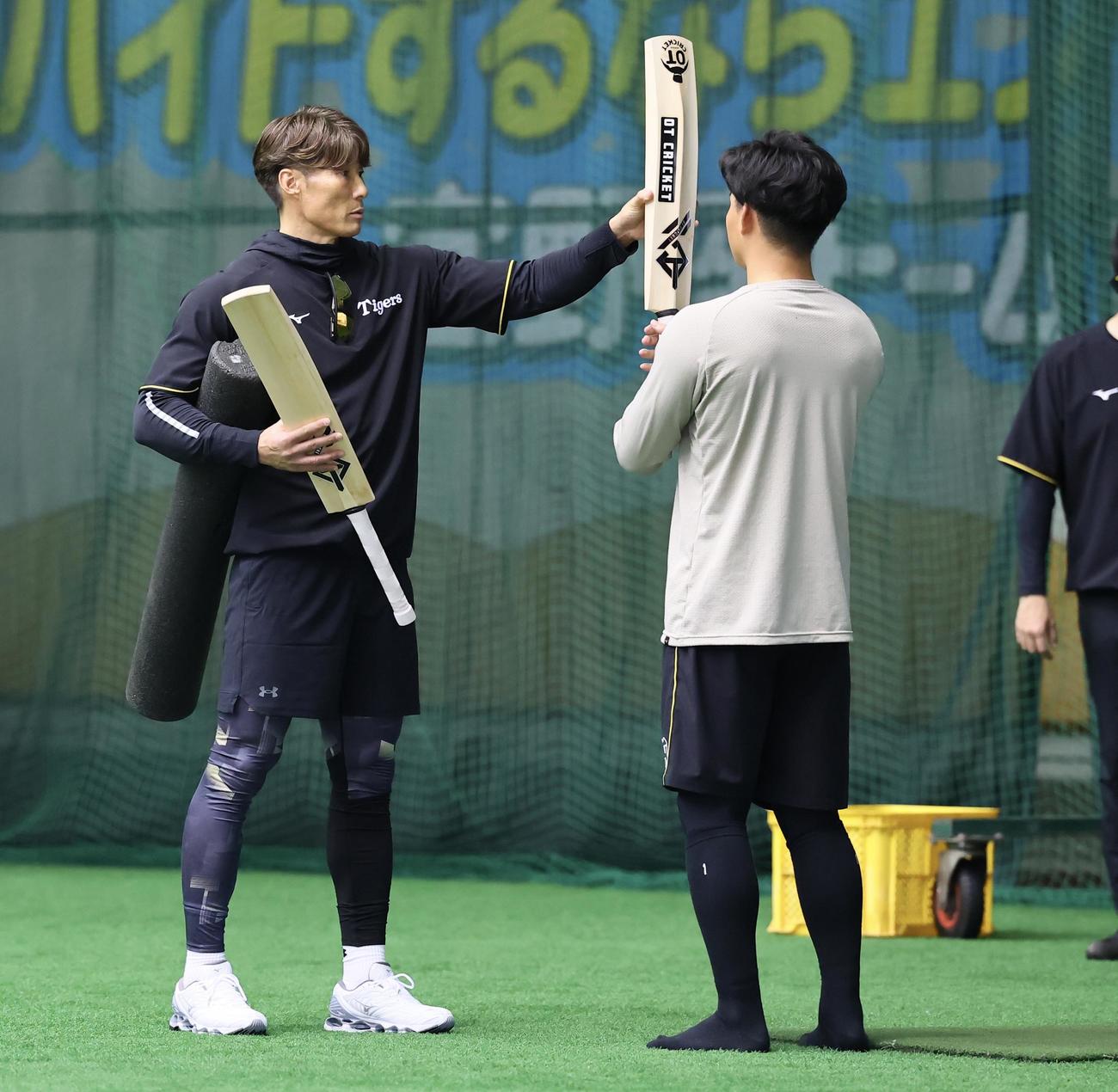 森下にクリケット型バットを渡す糸井臨時コーチ（撮影・藤尾明華）