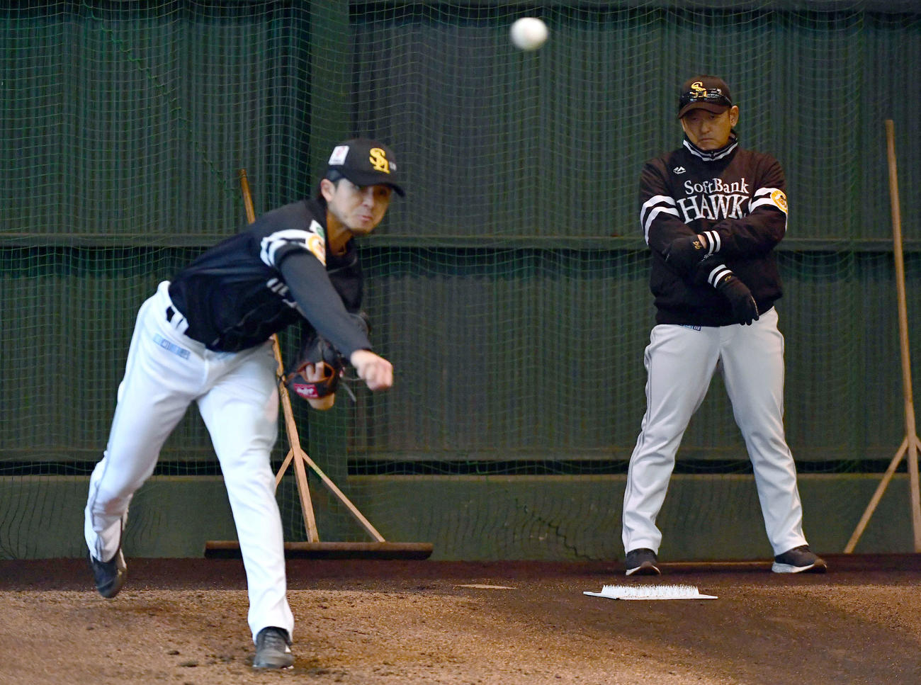 ブルペンで投げ込む上沢（左）を見つめるソフトバンク倉野コーチ（撮影・岩下翔太）