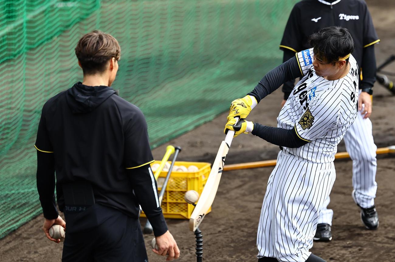 クリケットバットで打撃練習をする佐藤輝。左は糸井氏（撮影・上田博志）