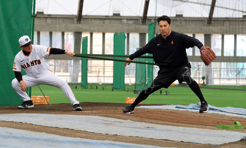 キャンプ3日目、ブルペンで巨人久保巡回投手コーチ（左）とチューブでトレーニングする田中将（撮影・浅見桂子）