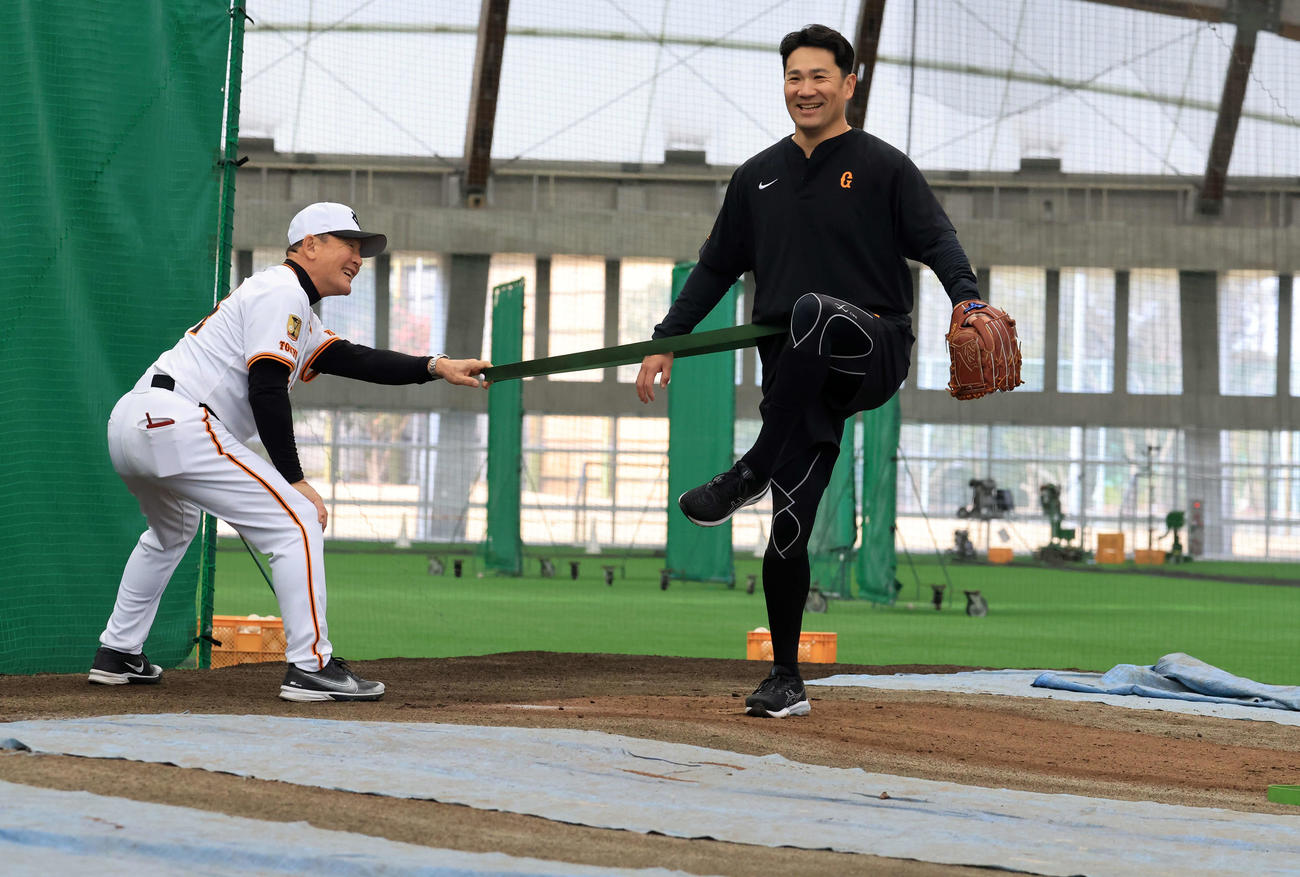 キャンプ3日目、ブルペンで巨人久保巡回投手コーチ（左）とチューブでトレーニングする田中将（撮影・浅見桂子）