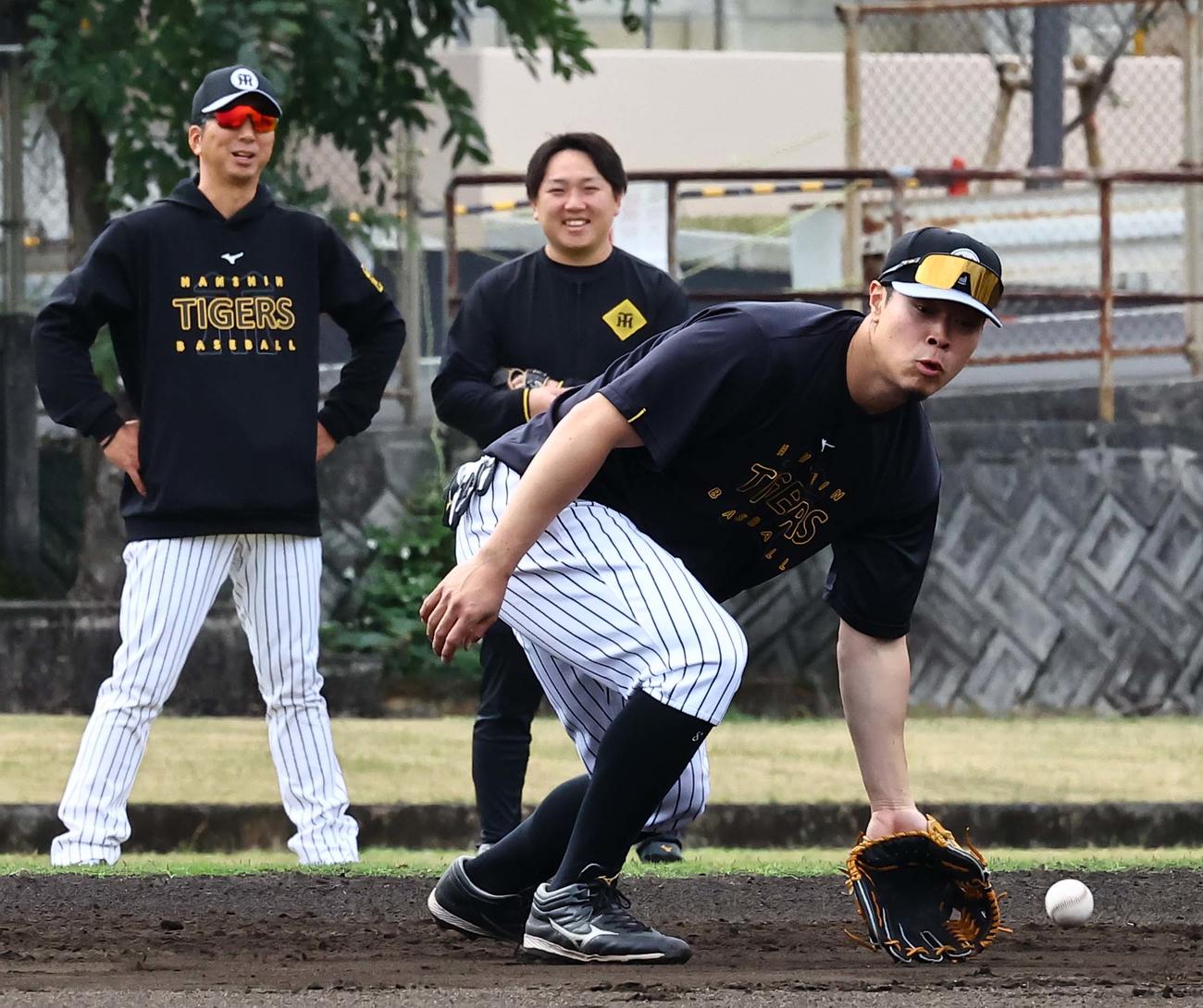 藤川監督（左）のチェックを受けながらノックを受ける佐藤輝（撮影・上田博志）