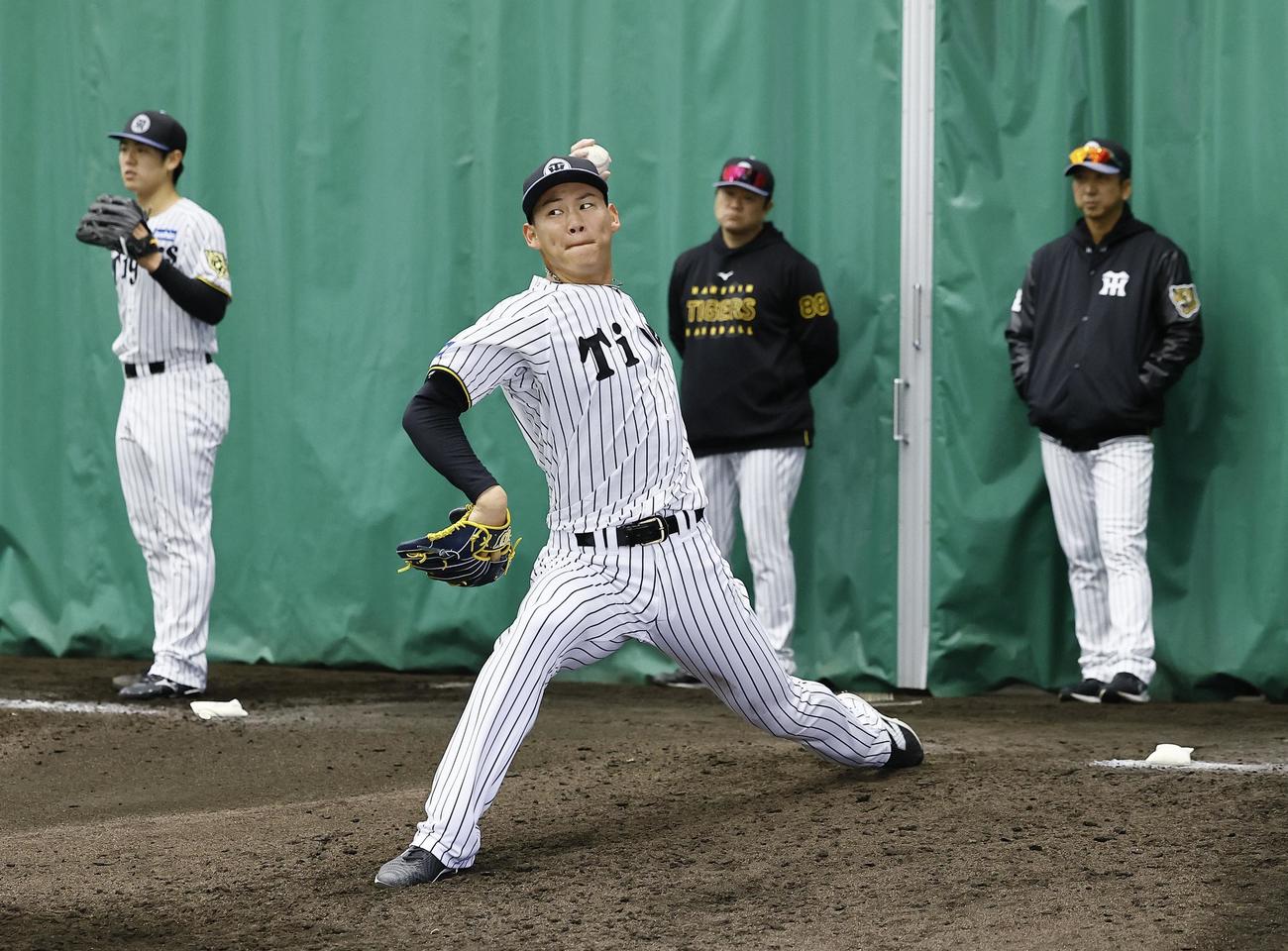 藤川球児監督（右）が見つめる中、ブルペンで100球以上を投げ込んだ及川（撮影・藤尾明華）