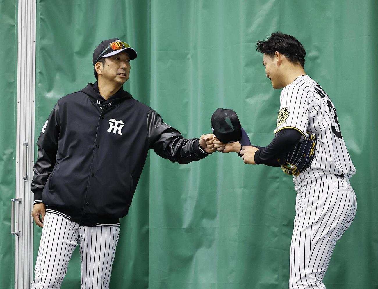 ブルペンで100球以上を投げ込んだ及川とグータッチを交わす藤川監督（撮影・藤尾明華）