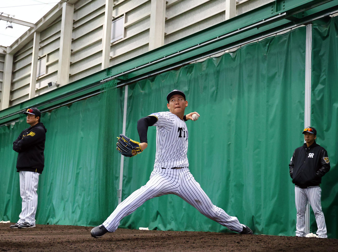 藤川監督（右）が見つめる中、ブルペンで投げ込む及川（撮影・藤尾明華）