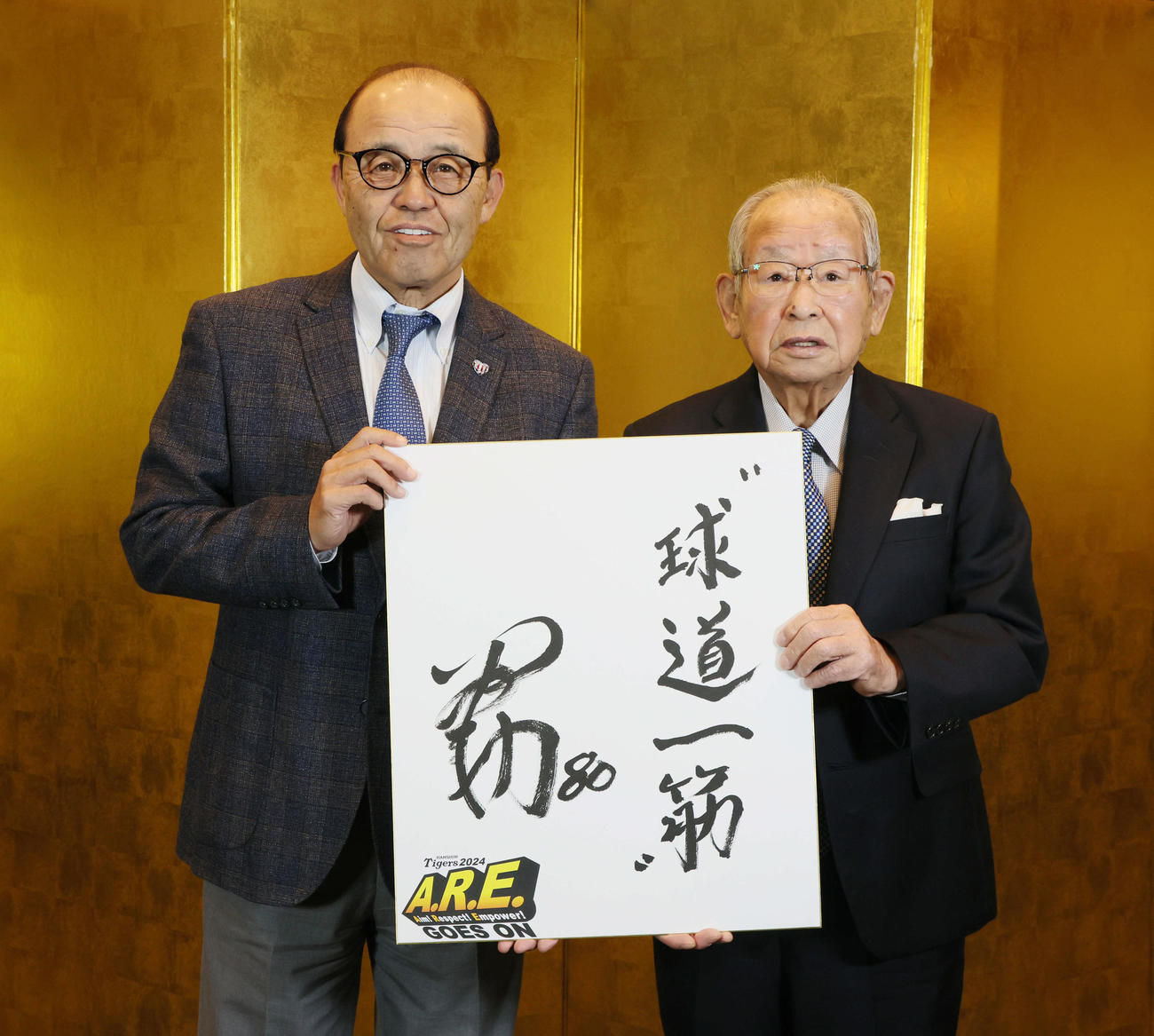 2023年12月、新たな座右の銘「球道一筋」と書かれた色紙を持つ岡田彰布監督と吉田義男さん（右）