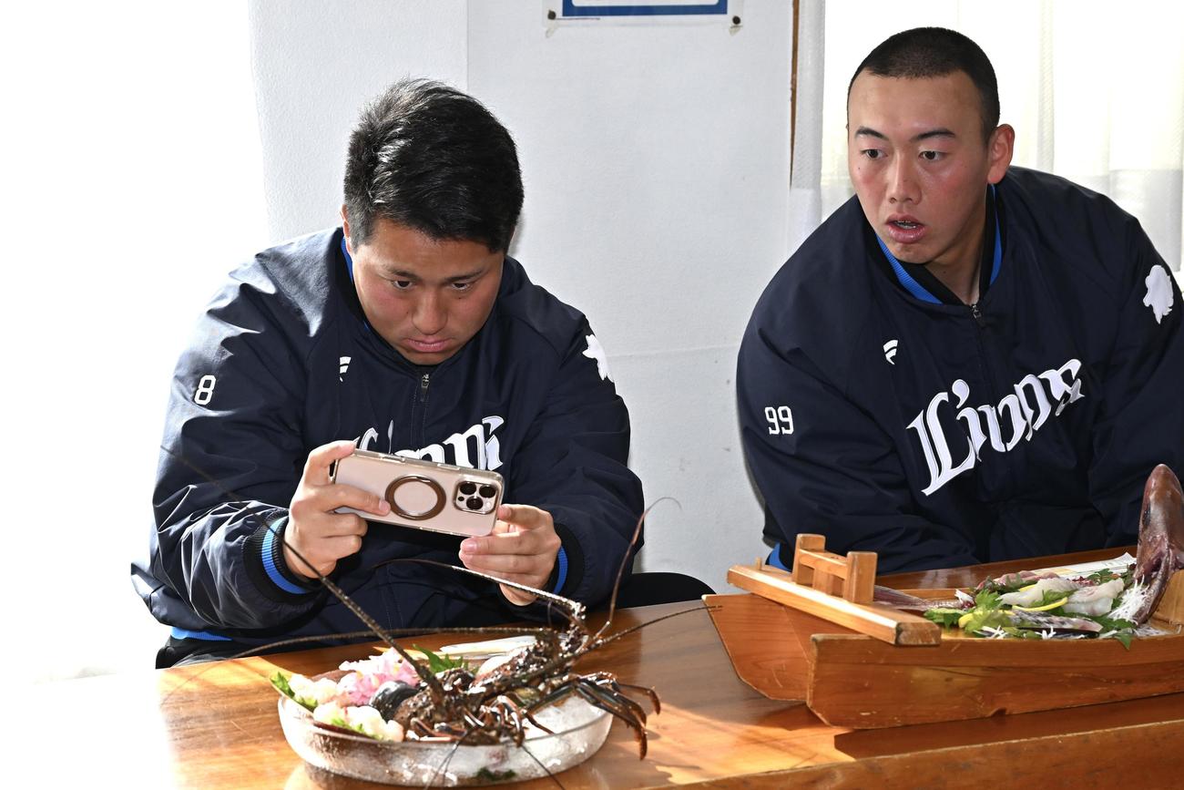 活け作りされた伊勢海老を撮影する西武渡部聖（左）と村田（撮影・滝沢徹郎）