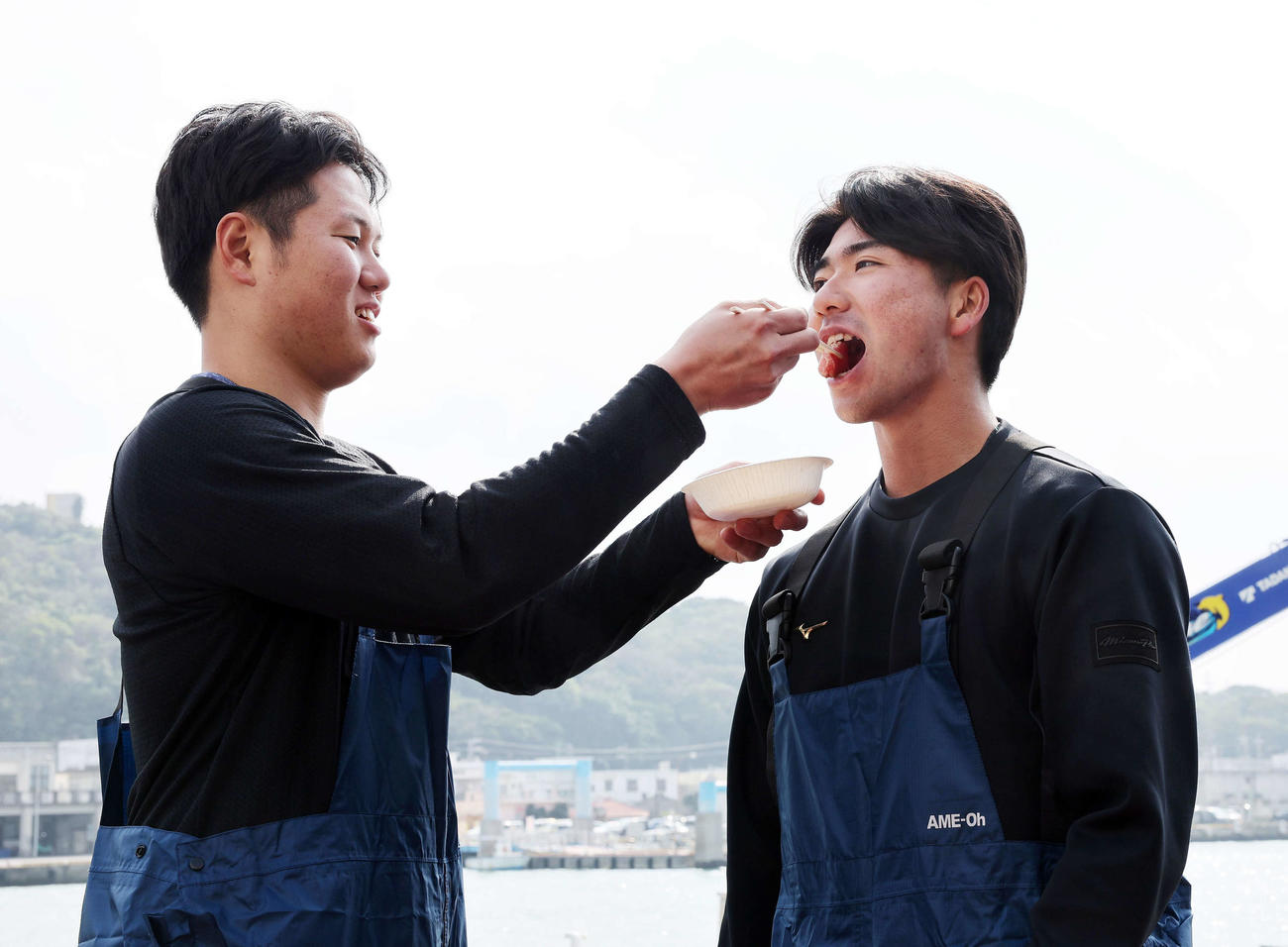 DeNA若松（左）からマグロを食べさせてもらう篠木（撮影・鈴木正人）
