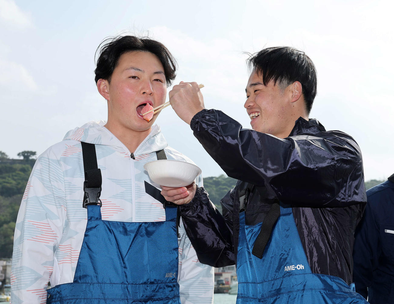 DeNA加藤（右）からマグロを食べさせてもらう竹田（撮影・鈴木正人）