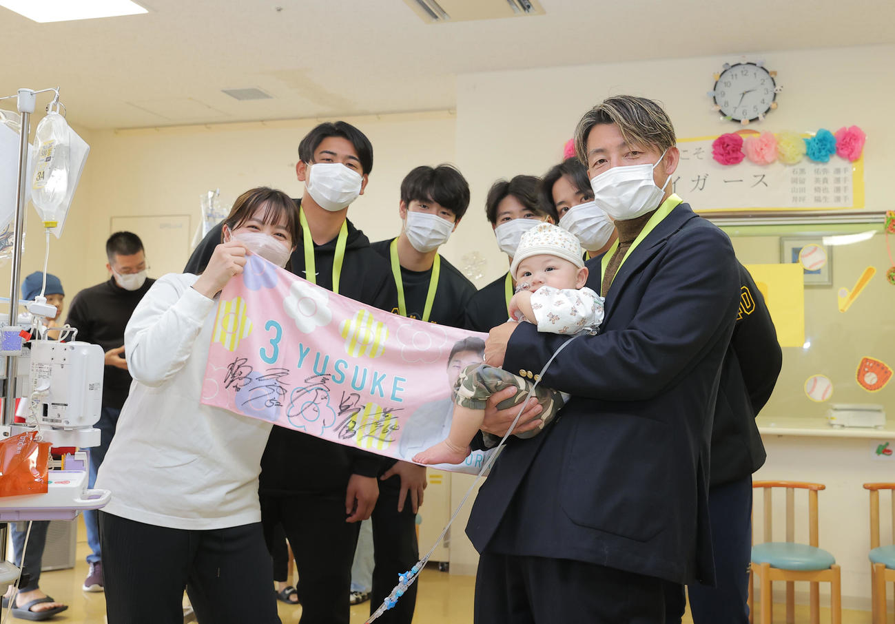 沖縄県立南部医療センター・こども医療センターを訪問し、子どもたちと触れ合う右から鳥谷敬氏、阪神井坪、山田、石黒、岡留