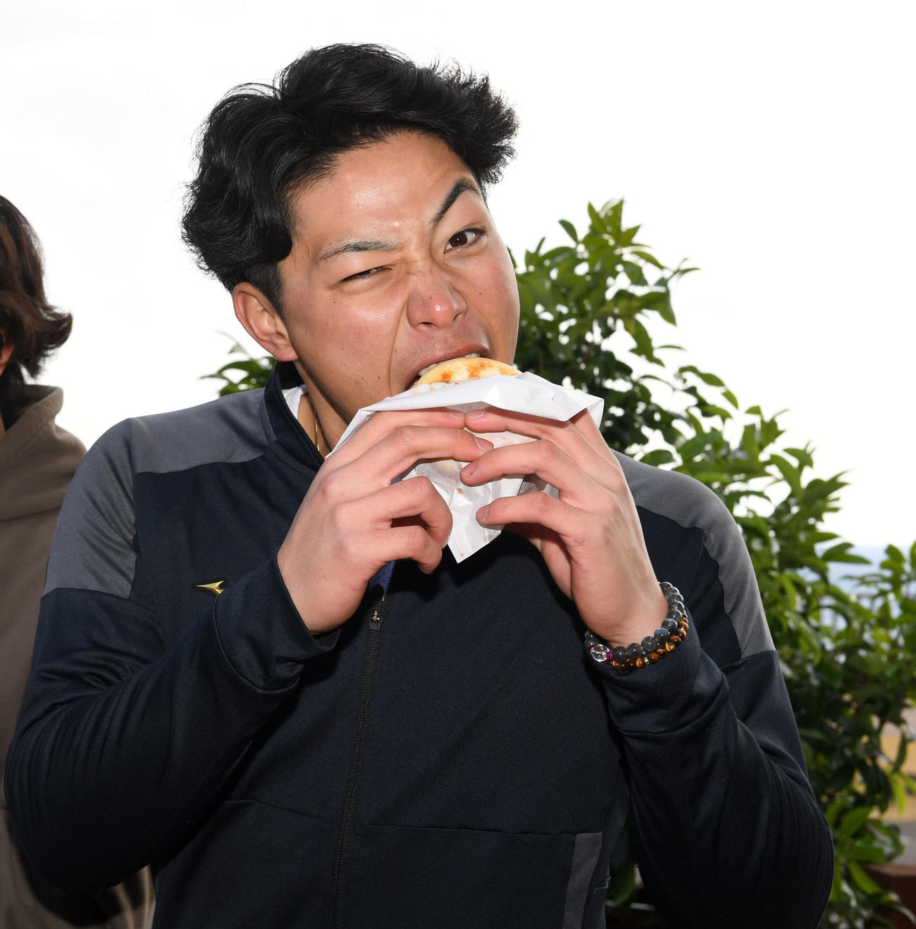 キャンプ休日に4月から発売されるチョウザメを使用した「ロイヤルフィッシュバーガー」を試食するオリックス麦谷（撮影・前岡正明）