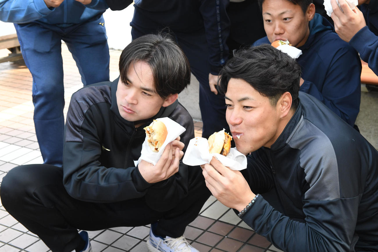 4月から発売されるチョウザメを使用した「ロイヤルフィッシュバーガー」を試食するオリックス麦谷（右）と寺西（撮影・前岡正明）