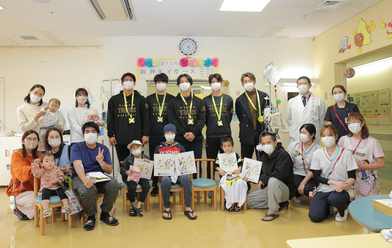 沖縄県立南部医療センター・こども医療センターを訪問し、子どもたちと触れ合う後方左から3人目から2人目から阪神岡留、石黒、井坪、山田、鳥谷敬氏