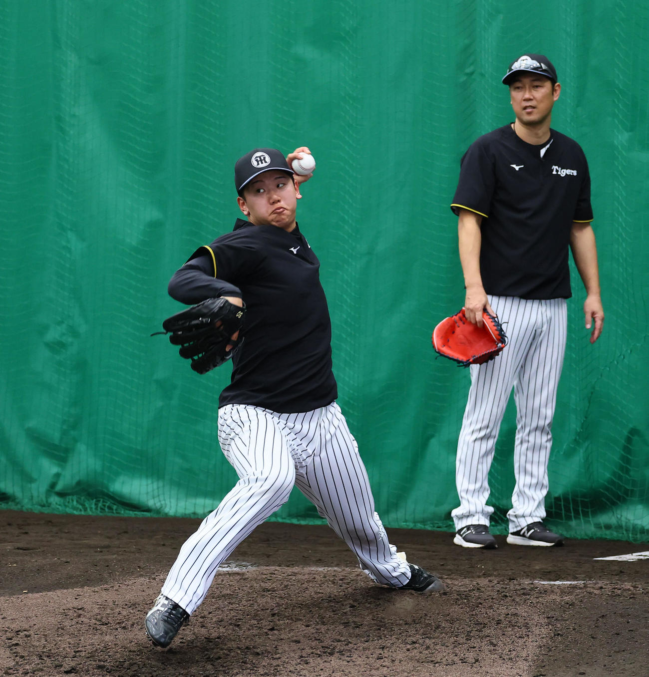 個別練習で金村投手コーチ（右）に指導を受けながら投球練習をする阪神門別（撮影・藤尾明華）