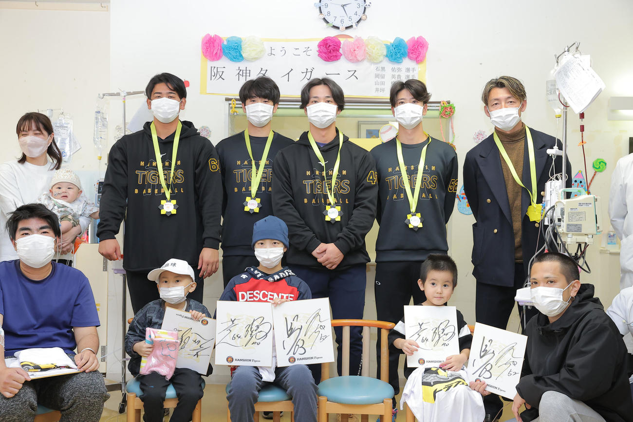 沖縄県立南部医療センター・こども医療センターを訪問し、子どもたちと触れ合う左から2人目から阪神岡留、石黒、井坪、山田、鳥谷敬氏