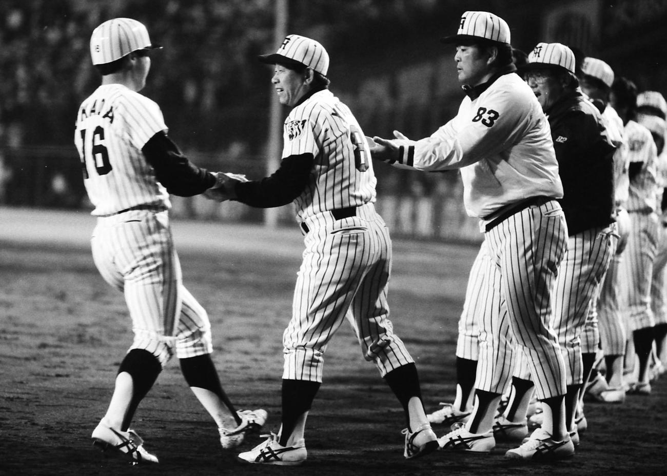85年4月17日、巨人戦の7回、バース、掛布に続き、バックスクリーンへ3連発を放った阪神岡田（左）を迎える吉田監督（中央）ら