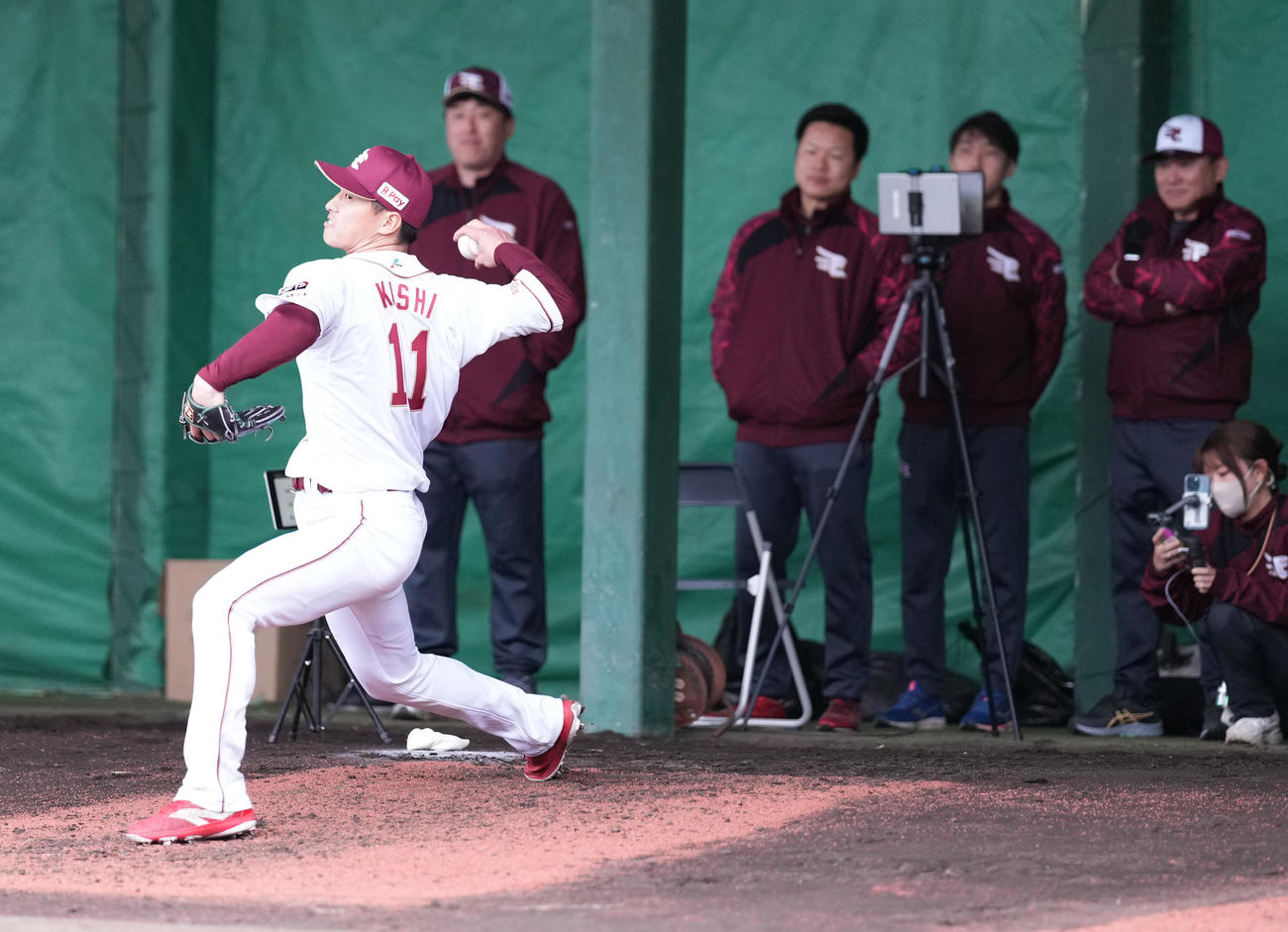 ブルペンで岸のユニホームを着て投球する楽天辰己。右上は三木谷オーナー、左奥は石井GM（撮影・鈴木みどり）