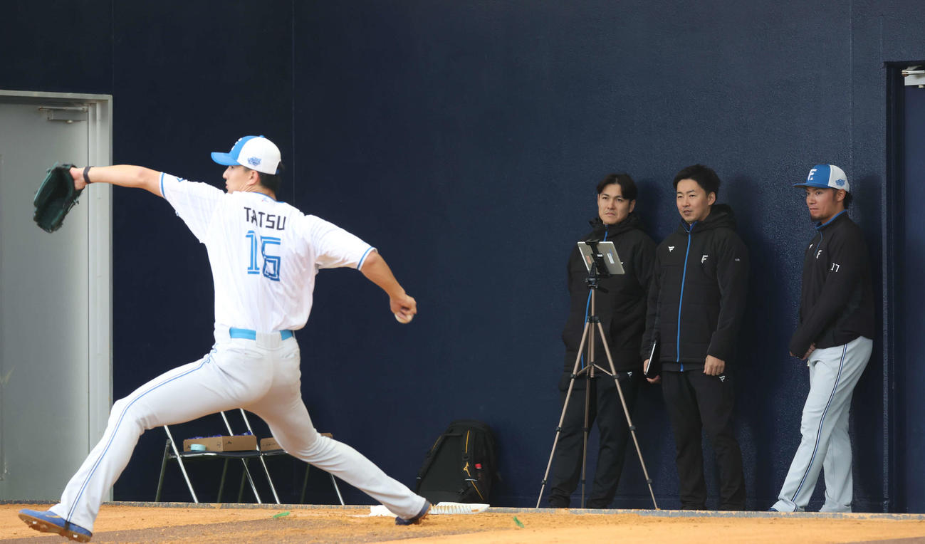 日本ハム伊藤（右）に見守られながらブルペンで投球する達（撮影・黒川智章）