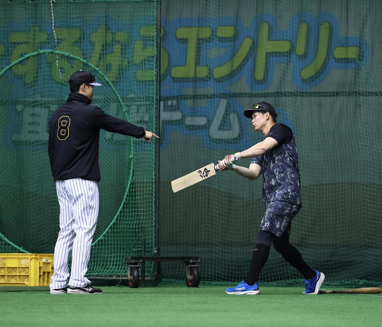 クリケットバットを手にした野口（右）と話をする佐藤輝（撮影・藤尾明華）